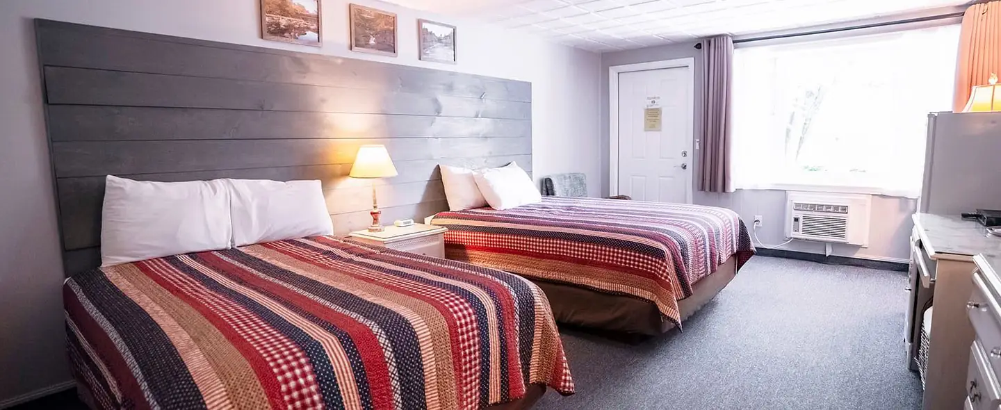 Guest room at Scenic Inn with two beds, a ceiling fan, and a wall-mounted TV